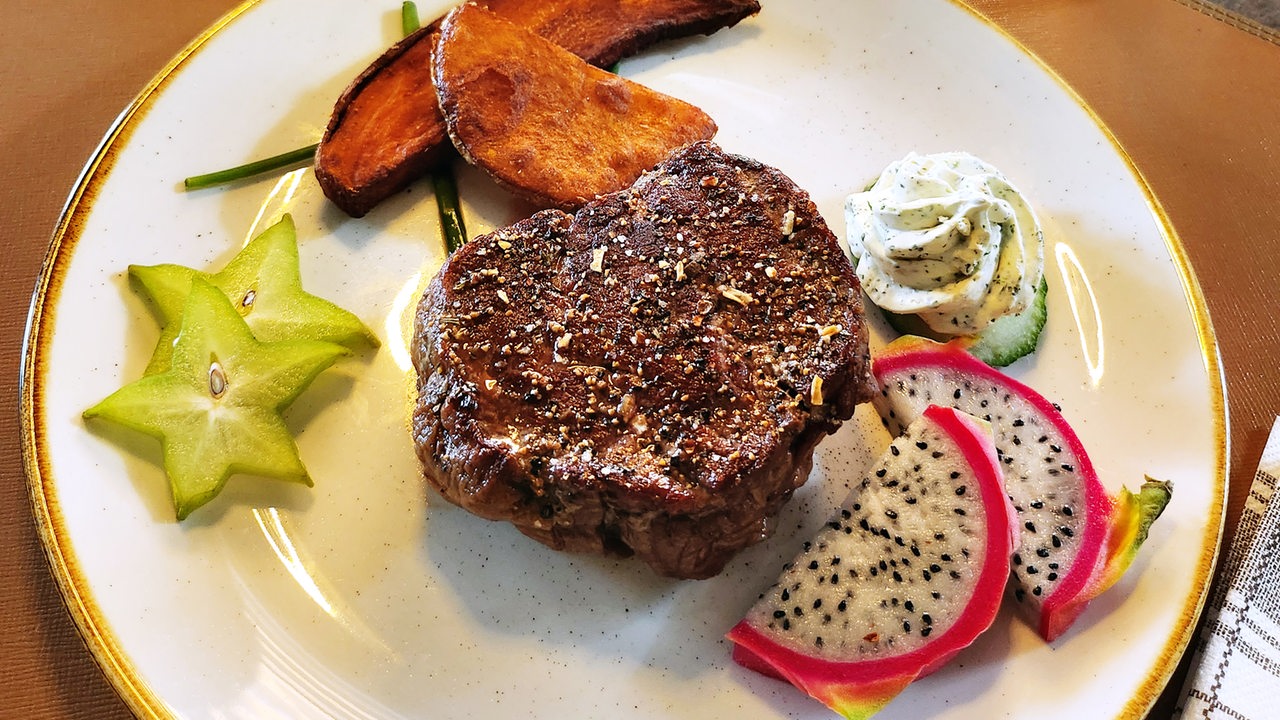 Ein gebratenes Steak liegt angerichtet auf einem Teller.