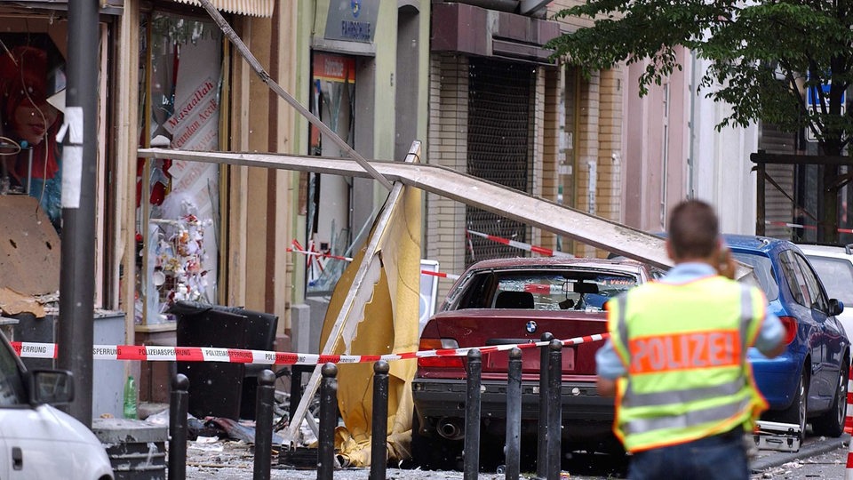 Ein Polizist sichert in Köln die Spuren einer Explosion in einer Wohnstraße.