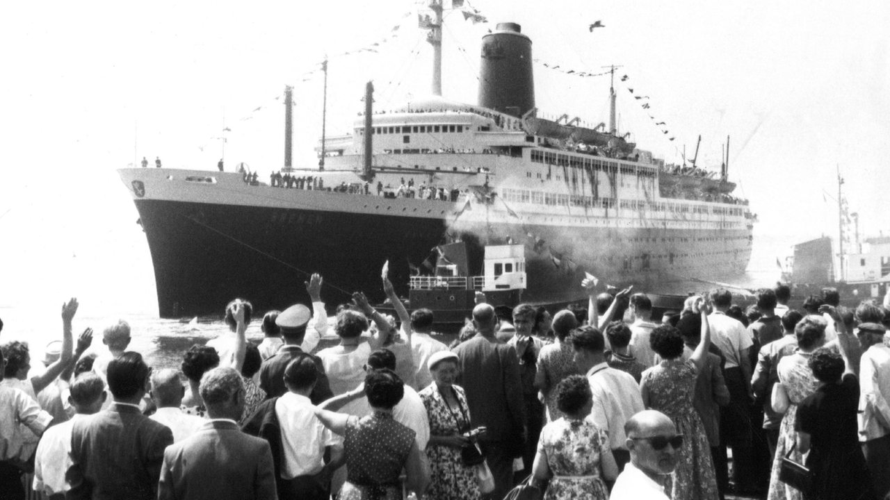 Auf dem Kai stehende Menschen winken dem Schiff hinterher. Pünktlich um zwölf Uhr am 9. Juli 1959 ist der Ozeanriese "Bremen" von Bremerhaven aus zu seiner Jungfernfahrt nach New York ausgelaufen.