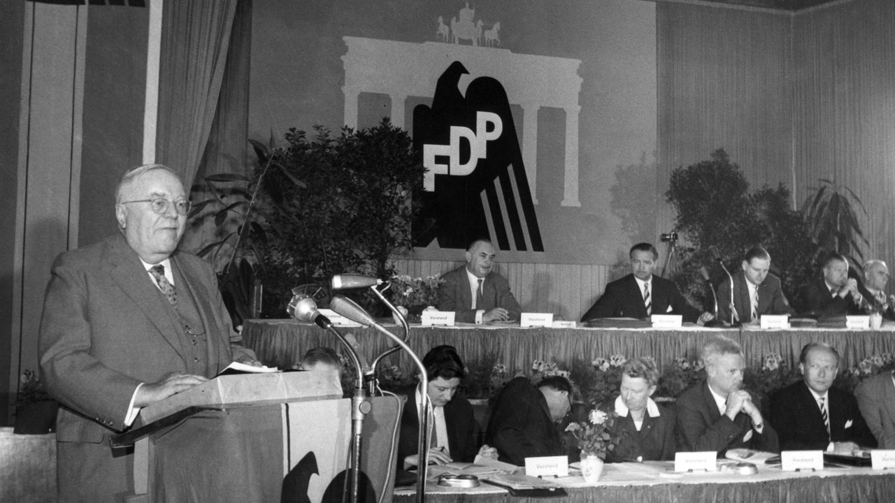 Der FDP-Bundesvorsitzende Dr. Reinhold Maier am Rednerpult während seines Grundsatzreferates, rechts dahinter der FDP-Vorstand 1959.