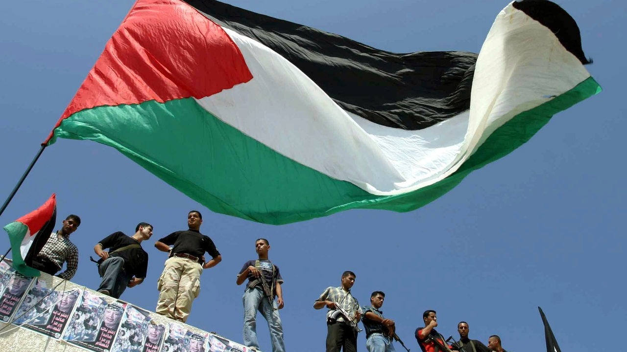 Militante Palästinenser und Fatah-Aktivisten stehen am 28.9.2003 während einer Demonstration in Gaza-Stadt im Gazastreifen auf dem Dach eines Gebäudes. Im Vordergrund weht eine palästinensische Flagge.