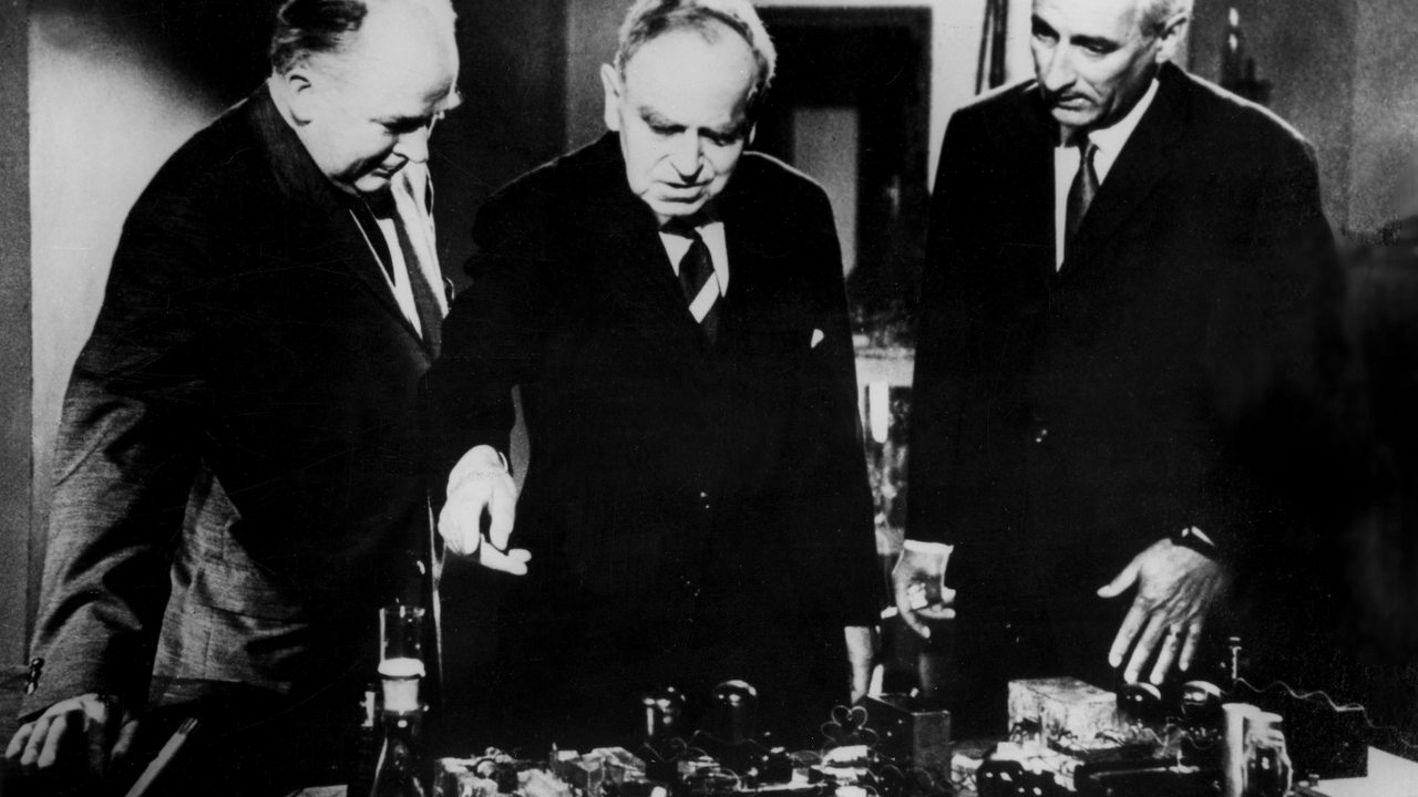 Fritz Straßmann und Otto Hahn führen einem Mann an einem Modell die Kernspaltung vor (Archivbild)