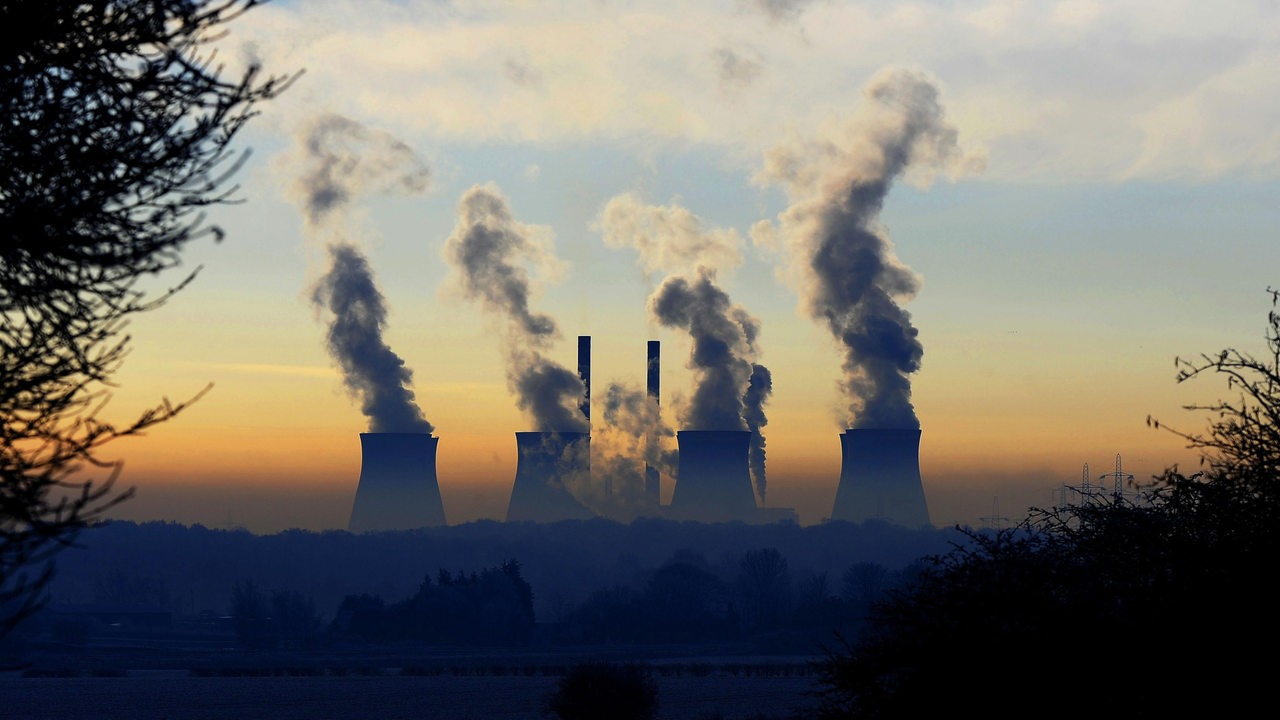 Ein Kraftwerk erhebt sich über dem Nebel und den frostbedeckten Feldern