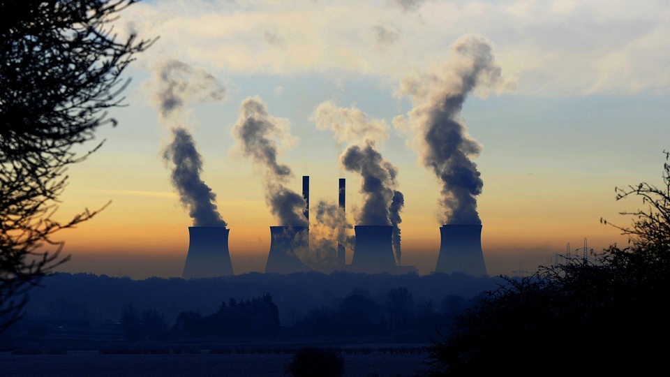 Ein Kraftwerk erhebt sich über dem Nebel und den frostbedeckten Feldern