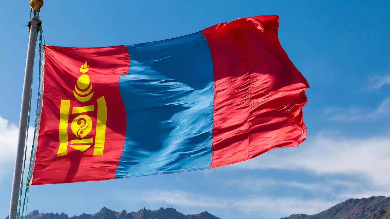 Die Nationalflagge der Mongolei vor blauem Himmel