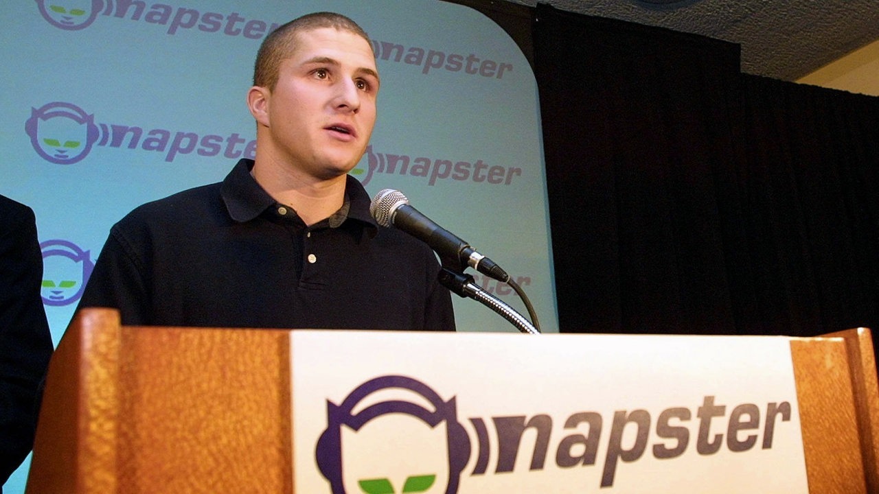 Der Gründer der Musiktauschbörse Napster, Shawn Fanning, am Mikrofon. Am Pult und im Hintergrund das Napster-Logo