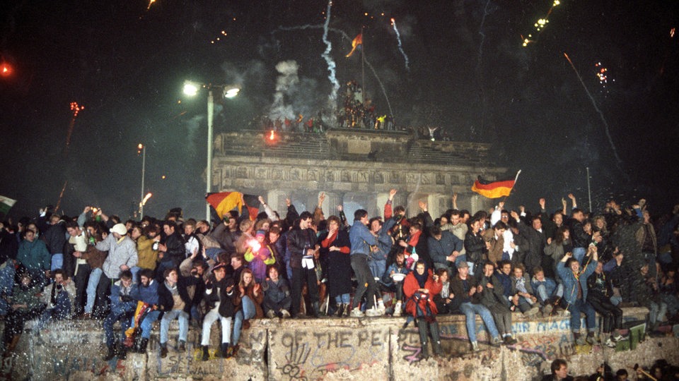 Ausgelassen feiern die Berliner am 31. Dezember 1989 Silvester auf der Berliner Mauer vor dem Brandenburger Tor. 