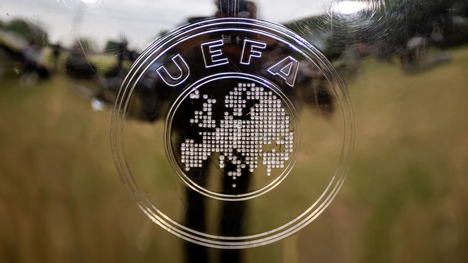Das UEFA-Logo ist auf einer Glasscheibe zu sehen. In der Spiegelung sieht man einen Garten und den Fotografen.
