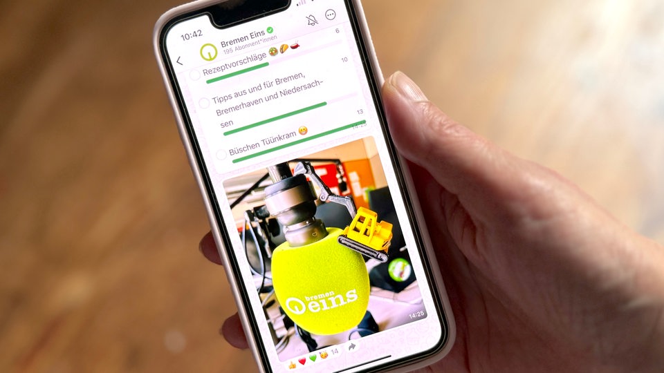 Eine Hand hält ein Smartphone mit dem Bremen-Eins-WhatsAppkanal
